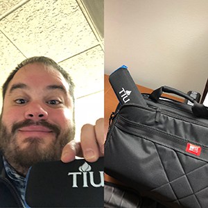 Man smiling and holding a fold-up umbrella, plus a fold-up umbrella inside a laptop bag