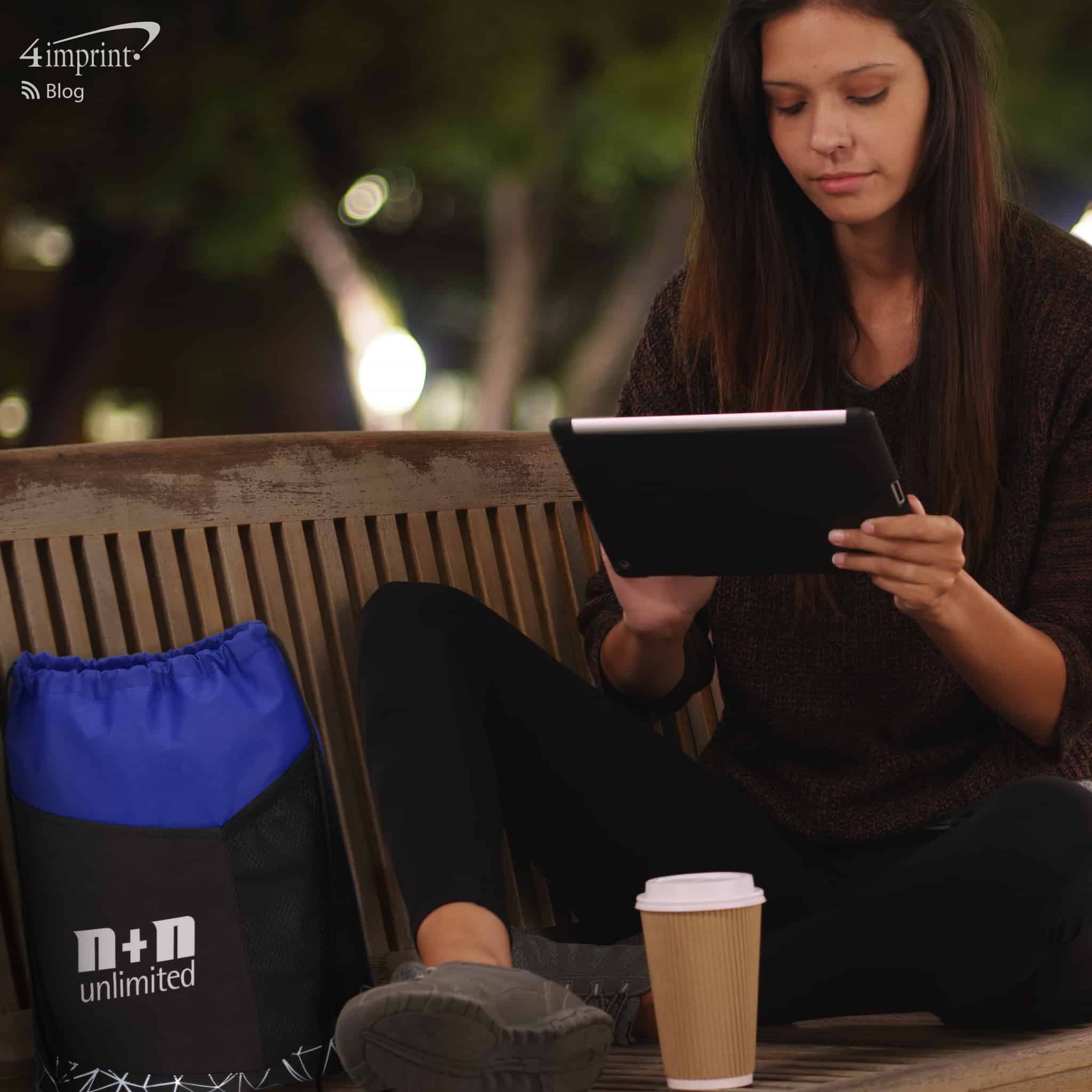Picture of woman sitting on park bench at night with a branded bag next to her l 4imprint reflective promotional items