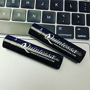 Two black lip balm sticks laying next to a keyboard