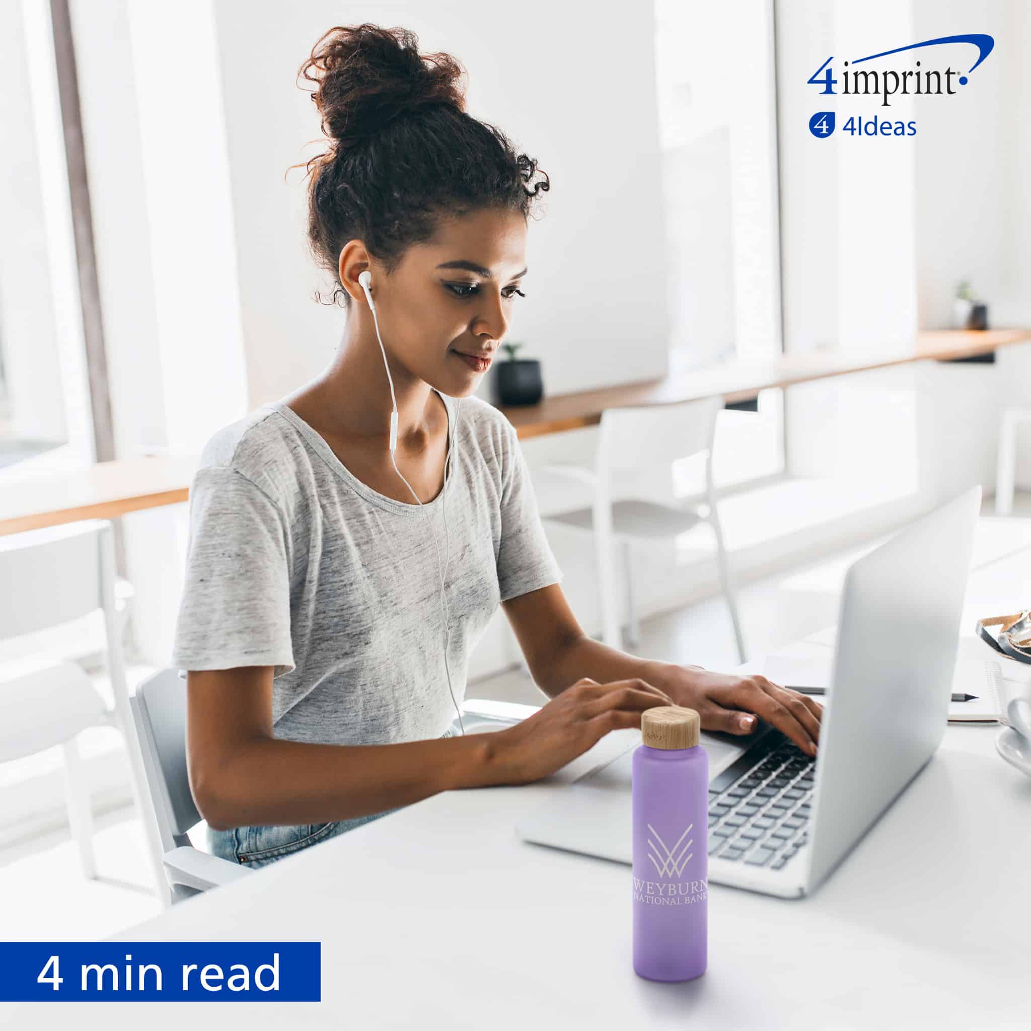 Woman wearing ear buds typing on laptop. A purple water bottle with a logo is on the desk.