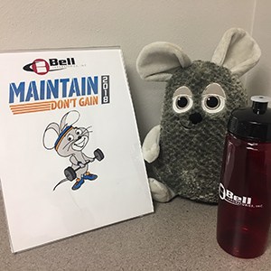 A Refresh Clutch Water Bottle next to a sign and stuffed animal. 