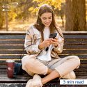 Woman on smartphone sitting on bench outdoors.