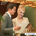 Woman and man in banquet hall setting looking at a tablet and a clipboard.