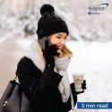 Smiling woman outside in cold-weather holding coffee and talking on phone.