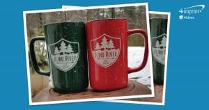 Two mugs imprinted with a logo in an outdoor winter scene.