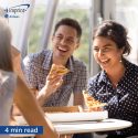 Woman laughing and eating pizza with coworkers