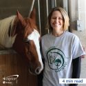 Woman wearing branded T-shirt standing by a horse.