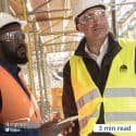 Two men in safety vests, helmets and goggles at a construction site.
