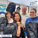 Smiling group of people holding branded backpacks