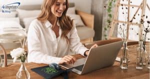 Woman working on laptop computer in home office setting.