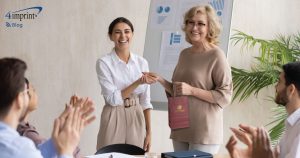 Two colleagues shaking hands. One is holding a gift bag.