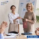 Two colleagues shaking hands. One is holding a gift bag.