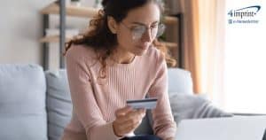 Woman holding credit card while typing on laptop computer.