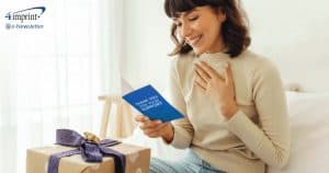 Smiling woman with a wrapped gift and thank-you card.