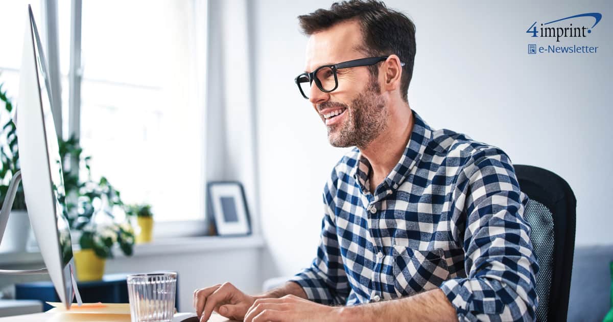 Smiling man wearing glasses and typing on wireless keyboard