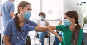 Young girl giving an elbow bump to female nurse in a clinic setting.