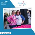 Two smiling women standing behind table with breast cancer giveaways at race.