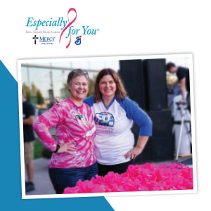 Two smiling women standing behind table with breast cancer giveaways at race.