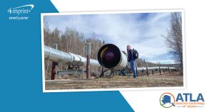 Person wearing a backpack and standing next to the Alyeska pipeline.