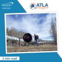 Person wearing a backpack and standing next to the Alyeska pipeline.