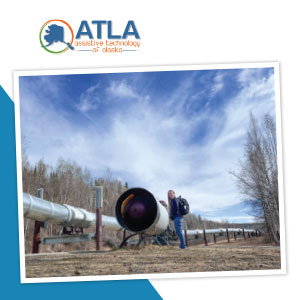 Person wearing a backpack and standing next to the Alyeska pipeline.