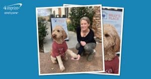 Woman shaking hands with a dog wearing a T-shirt.