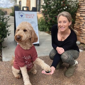 Woman shaking hands with a dog wearing a T-shirt.