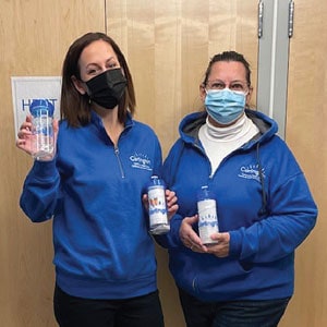 Two women holding up water bottles with a logo.