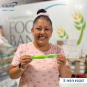Smiling woman holding neon green reusable cutlery set with a logo.