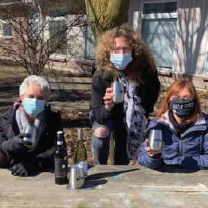 Three women holding promotional wine tumblers.