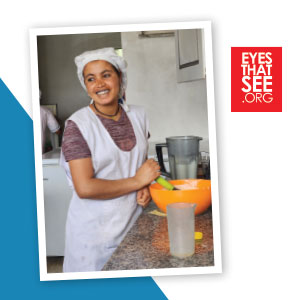 Ethiopian woman with a whisk and bowl in a kitchen.