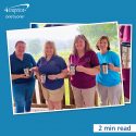 Four people in branded shirts holding travel mugs with a logo.