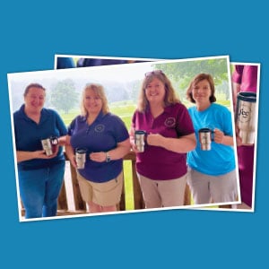 Four people in branded shirts holding travel mugs with a logo.