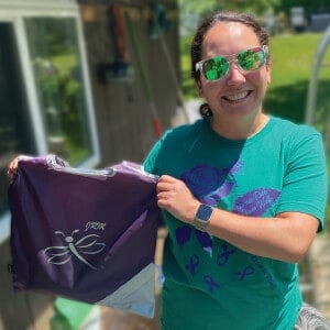 Woman holding up bag with a logo.