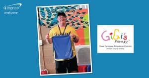 A young man who has Down syndrome is holding a branded golf towel.