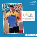A young man who has Down syndrome is holding a branded golf towel.