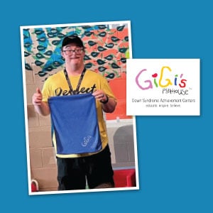 A young man who has Down syndrome is holding a branded golf towel.