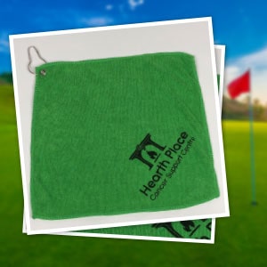 Hearth Place Cancer Support Centre branded golf towel with a golf course in the background.