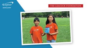 Two youth in an outdoor park setting are holding branded water bottles.