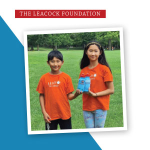 Two youth in an outdoor park setting are holding branded water bottles.