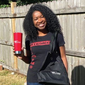 Woman holding a bright red tumbler with a logo.