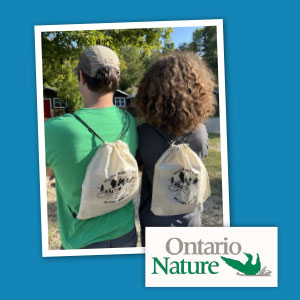 Two youth, with their backs facing the camera, wearing branded drawstring bags.