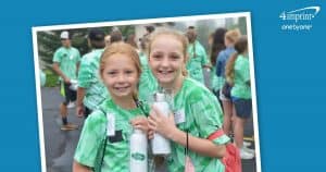 Two young girls in matching green shirts holding branded water bottles.