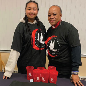 Two people in branded T-shirts standing behind a display of imprinted tumblers.