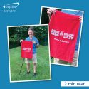 Man holding a red branded golf towel.