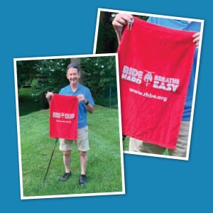 Man holding a red branded golf towel.