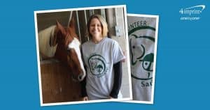 Woman wearing a branded T-shirt standing next to a horse.
