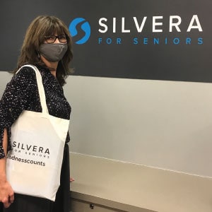 Woman holding a tote bag with a logo.