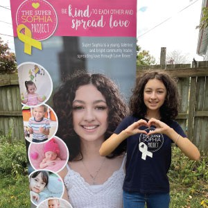 Young girl standing by promotional banner.