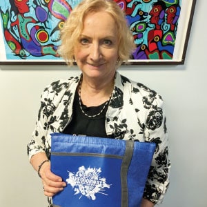 Woman holding a blue bag with a logo.